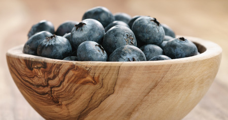Closeup   of fresh blueberries in wood bowl on tableの写真素材