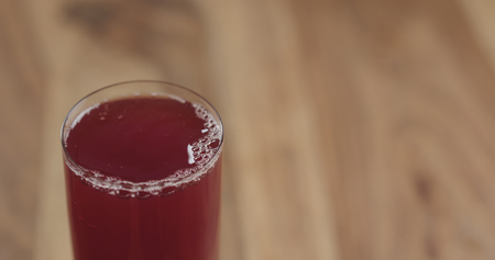 Closeup cranberry juice into the glass on wood tableの写真素材