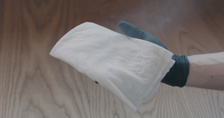 Closeup man in gloves cleaning ash wood floor with wet cloth