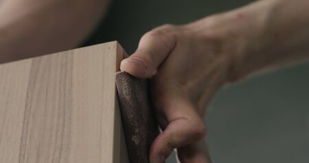 woodworker hand sanding black walnut drawer tray