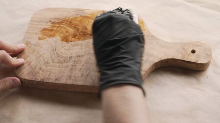 woodworker applying oil finish to olive wood board from aboveの写真素材