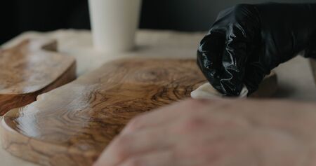 woodworker applying oil finish to olive wood boardの写真素材