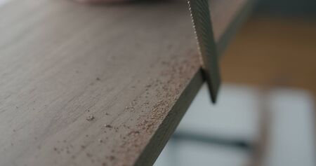 woodworker hand sanding walnut board with fileの写真素材