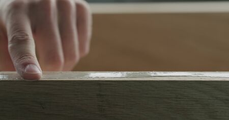 closeup man spreading wood glue on oak board with finger