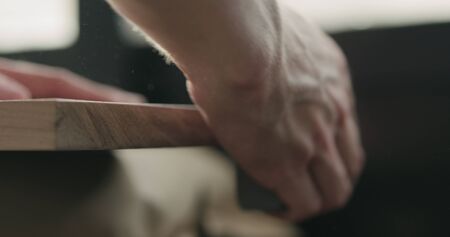 Woodworker hand sanding walnut board with sand blockの写真素材