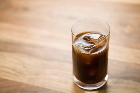 Glass of iced coffee on wooden table