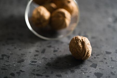 inshell walnuts fall of glass container on concrete terrazzo countertop
