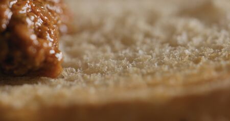 Extreme closeup spread red pesto on ciabatta slice
