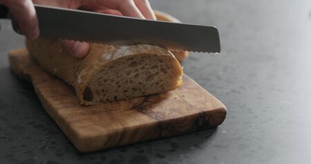 man hand slicing ciabatta on olive board, wide photo