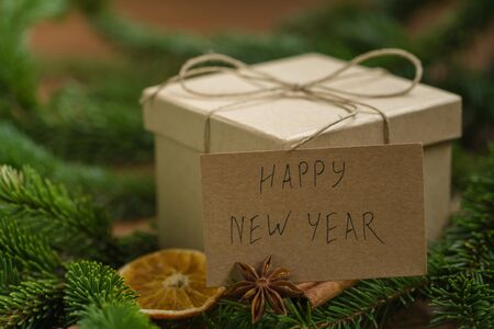 Eco brown paper gift box surrounded by christmas decorations and spruce branches with happy new year cardの写真素材