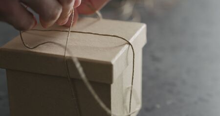 man hand ties bow on brown paper box