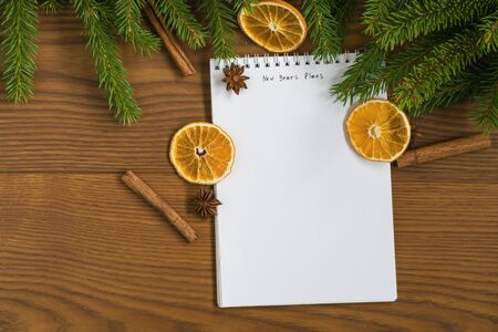 Flat lay new years plans notepad with spruce twigs and decorations on ash wood surfaceの写真素材