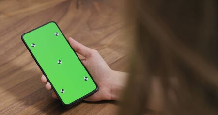 young woman holding smartphone over walnut tableの写真素材