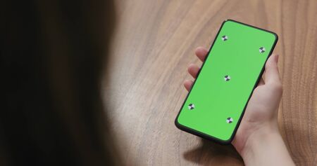 young woman holding smartphone over walnut tableの写真素材