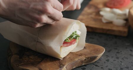 man hands packing ciabatta sandwich with salami and cheeseの写真素材