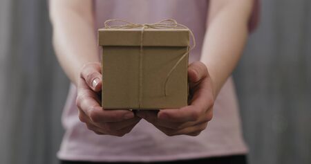 young woman stand and show brown gift box with twine bowの写真素材
