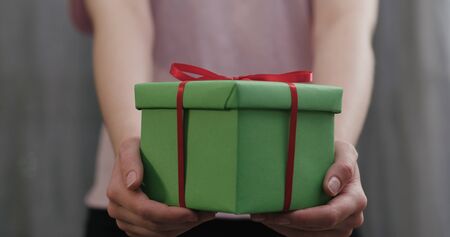 young woman stand and show green gift box with red ribbon bowの写真素材