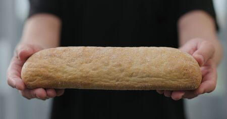 man hands show hot ciabatta bread indoorsの写真素材