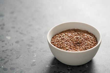 Flax seeds in white bowl on terrazzo surface with copy spaceの写真素材