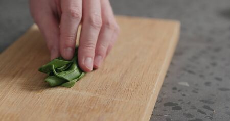 man chopping fresh spinach leaves on oak cutting boardの写真素材