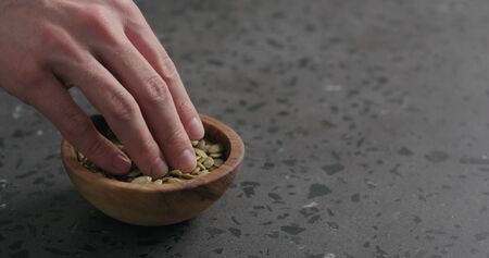 man hand takes pumpkin seeds from olive bowl with copy spaceの写真素材