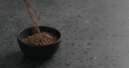 flaxseed falling into black bowl on terrazzo countertopの写真素材