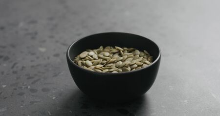 pumpkin seeds in black bowl on terrazzo countertop with copy spaceの写真素材
