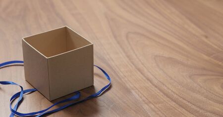 man hands opens eco friendly paper gift box with blue ribbon on walnut table with copy space