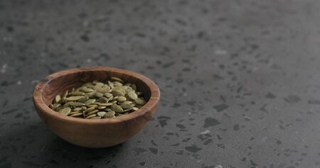 pumpkin seeds in olive bowl on terrazzo countertop with copy spaceの写真素材
