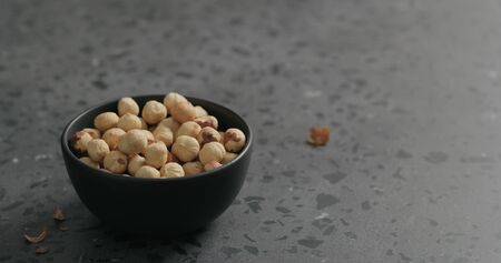 oasted hazelnuts in black bowl on terrazzo countertop, wide photoの写真素材