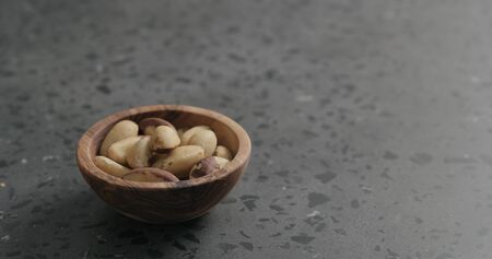 brazil nuts in olive bowl on terrazzo countertop, wide photo