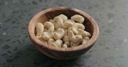 cashew nuts in olive bowl on terrazzo countertop, wide photo