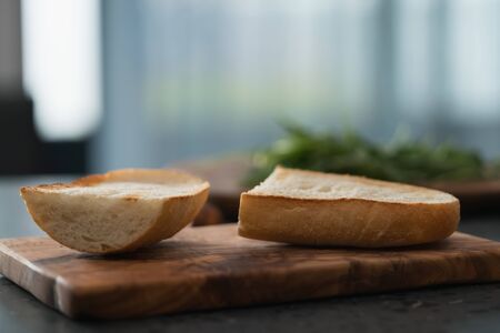 Toasted half of ciabatta for sandwich on olive board, shallow focusの写真素材