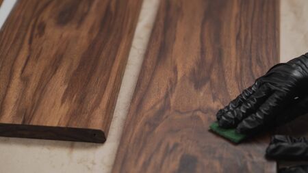 man sanding black walnut after oil application with abrasive pad, wide photo