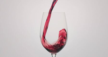 red wine pour into wineglass on neutral background, wide photoの写真素材
