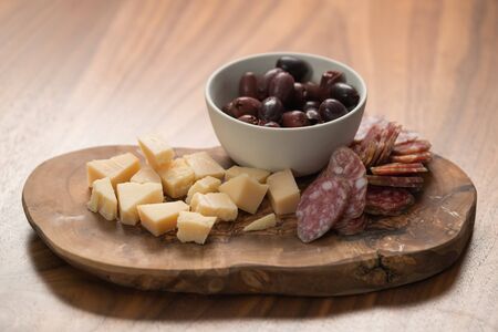 Italian antipasti with cheese olives and sausage on olive wood board