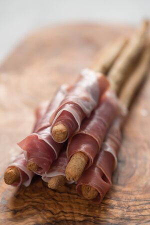 Grissini with prosciutto on olive wood boardの写真素材