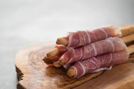 Grissini with prosciutto on olive wood board with copy spaceの写真素材