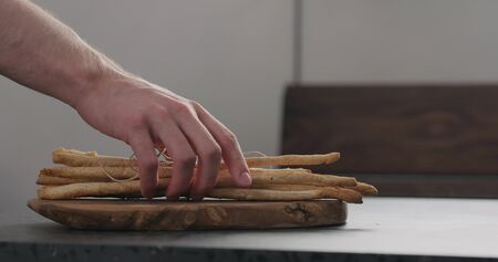 man hand take bunch of homemade grissini from olive board