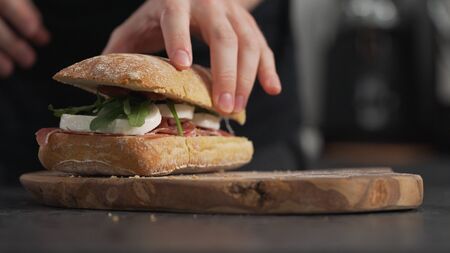man add top bun on ciabatta on olive boardの写真素材