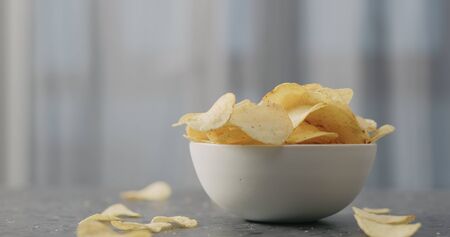 potato chips with plack pepper from white bowl on concrtete countertop, wide photoの写真素材