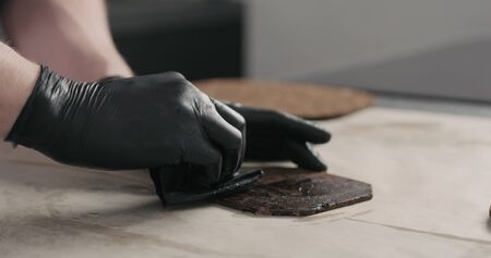man hands applying oil finish on dark cork coaster, wide photoの写真素材