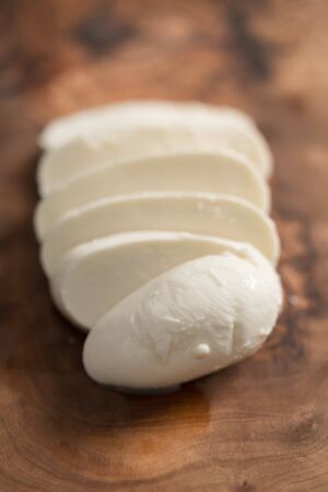 sliced mozzarella cheese on olive wood board, shallow focusの写真素材