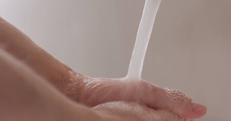 man washing hands under faucet closeup