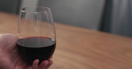 man hand take wineglass with red wine from walnut table with copy spaceの写真素材