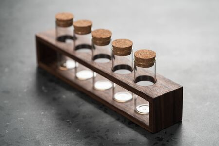 walnut holder with glass tubes for spices on concrete surface, shallow focusの写真素材