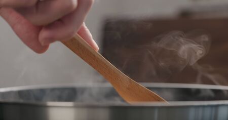 shot of frying turkey fillet pieces on nonstick pan and turning them with wood spatulaの写真素材