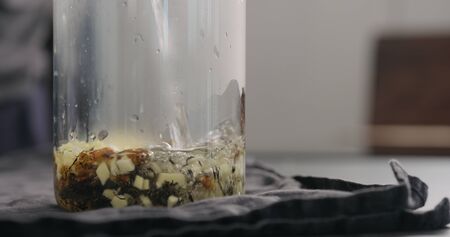 pour black tea with ginger and seaberry with hot water in glass beaker on kitchen countertop, wide photoの写真素材