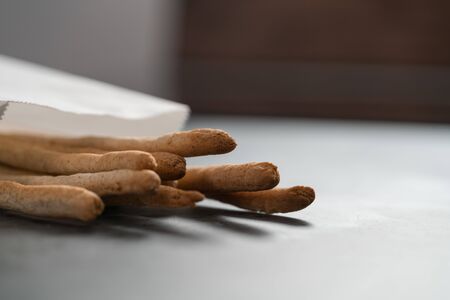 Traditional italian snack - grissini in white paper bag on concrete surfaceの写真素材