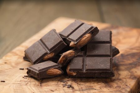 homemade dark chocolate with almonds on olive wood surface, shallow focusの写真素材
